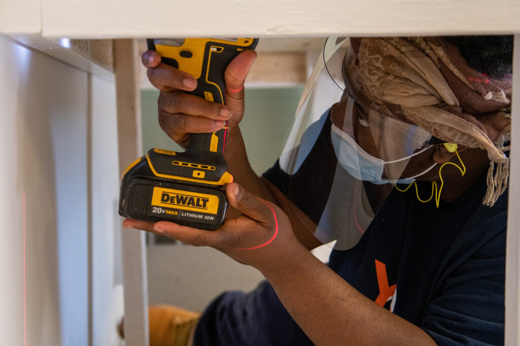 Student drills under a desk