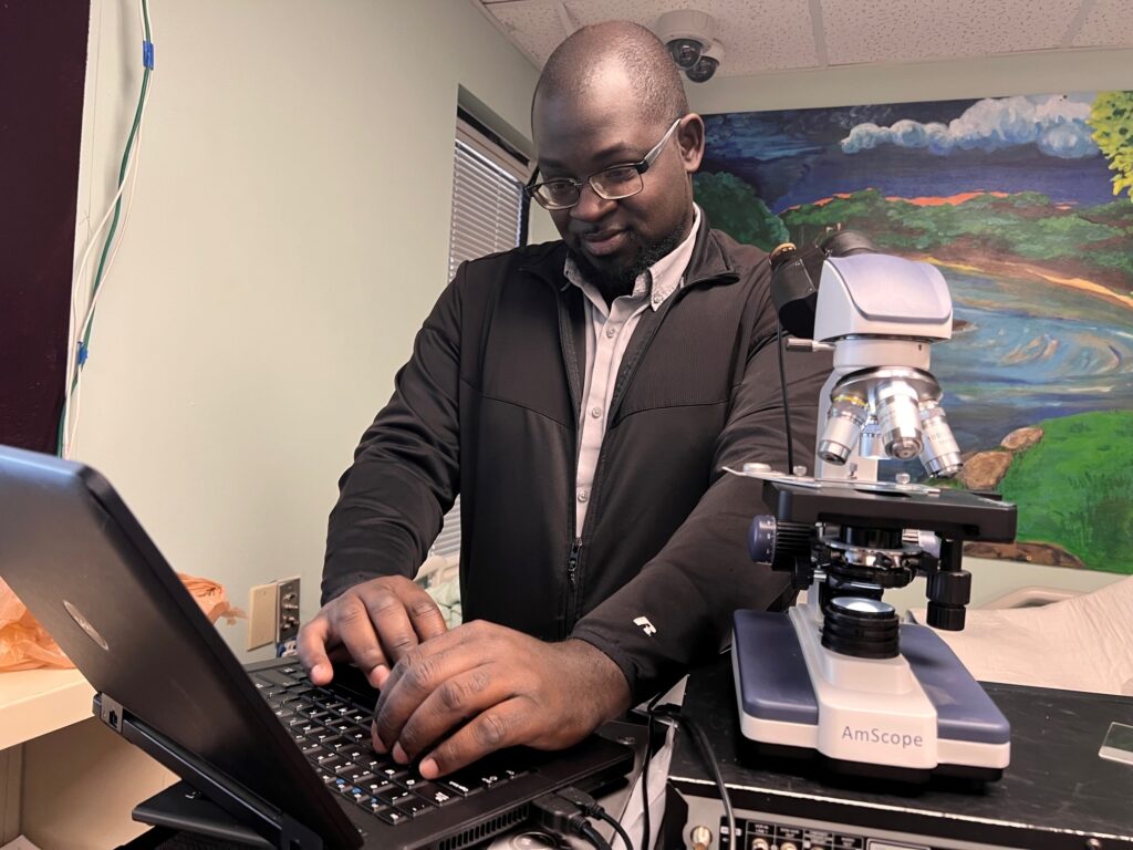 An person uses a laptop connected to a microscope.