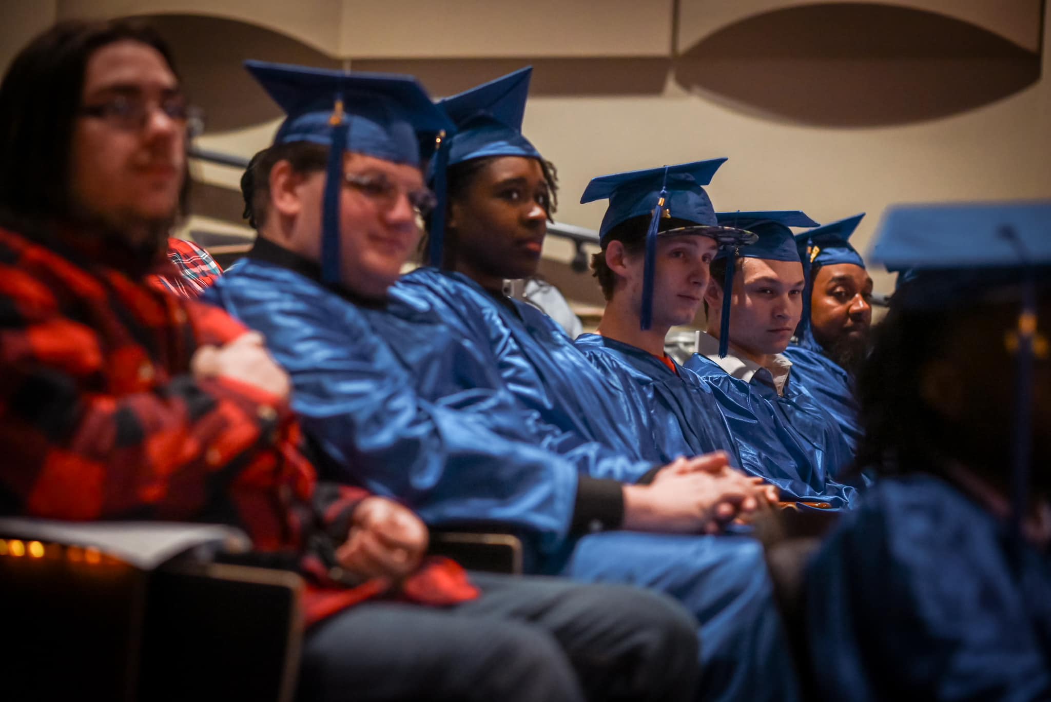 students sitting in their caps and gowns at graduation.