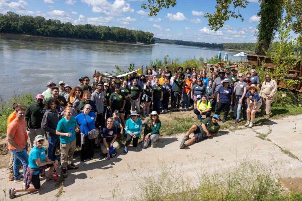 a large group of people stand together on the boat ramp at Cooper's Landing on the Missouri River.