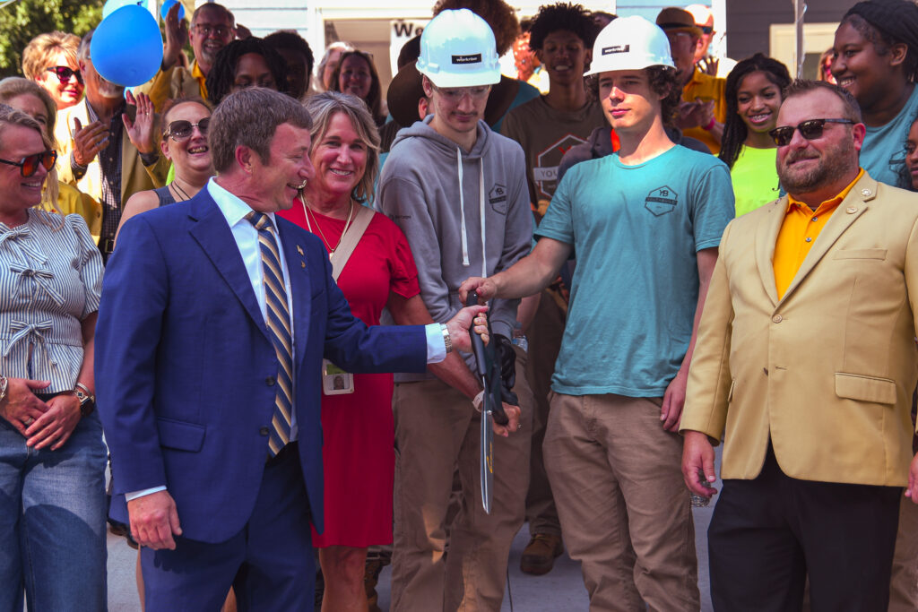 Students and ambassadors smile after the ribbon has been cut.