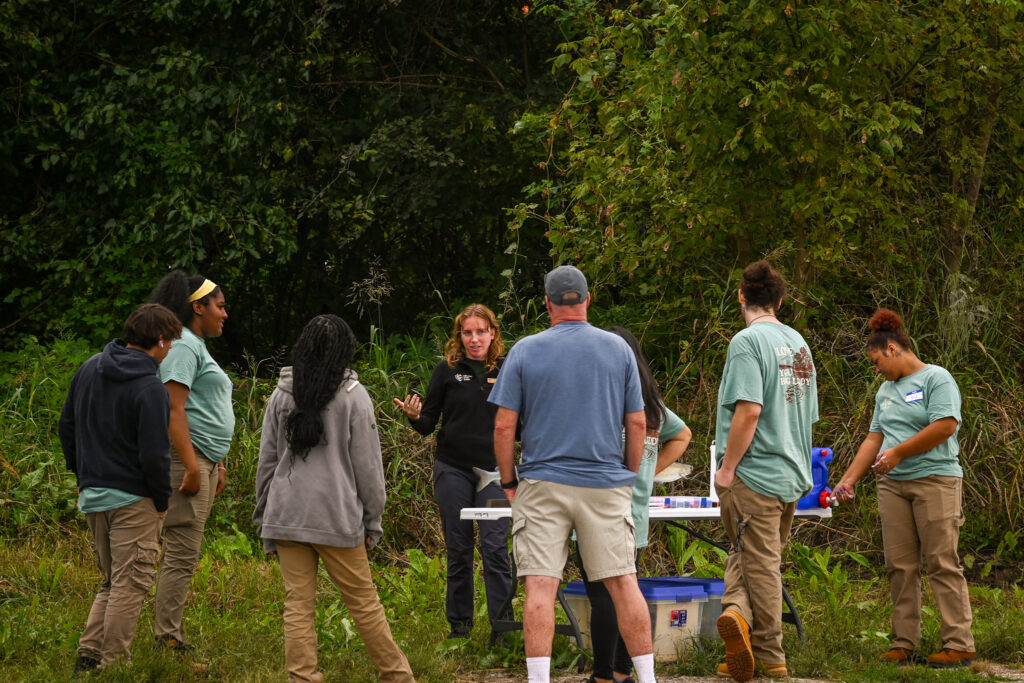 Students stand at a table as an instructor explains species of catfish.