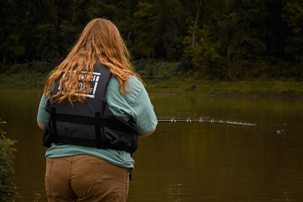 A young woman holds her fishing pole.